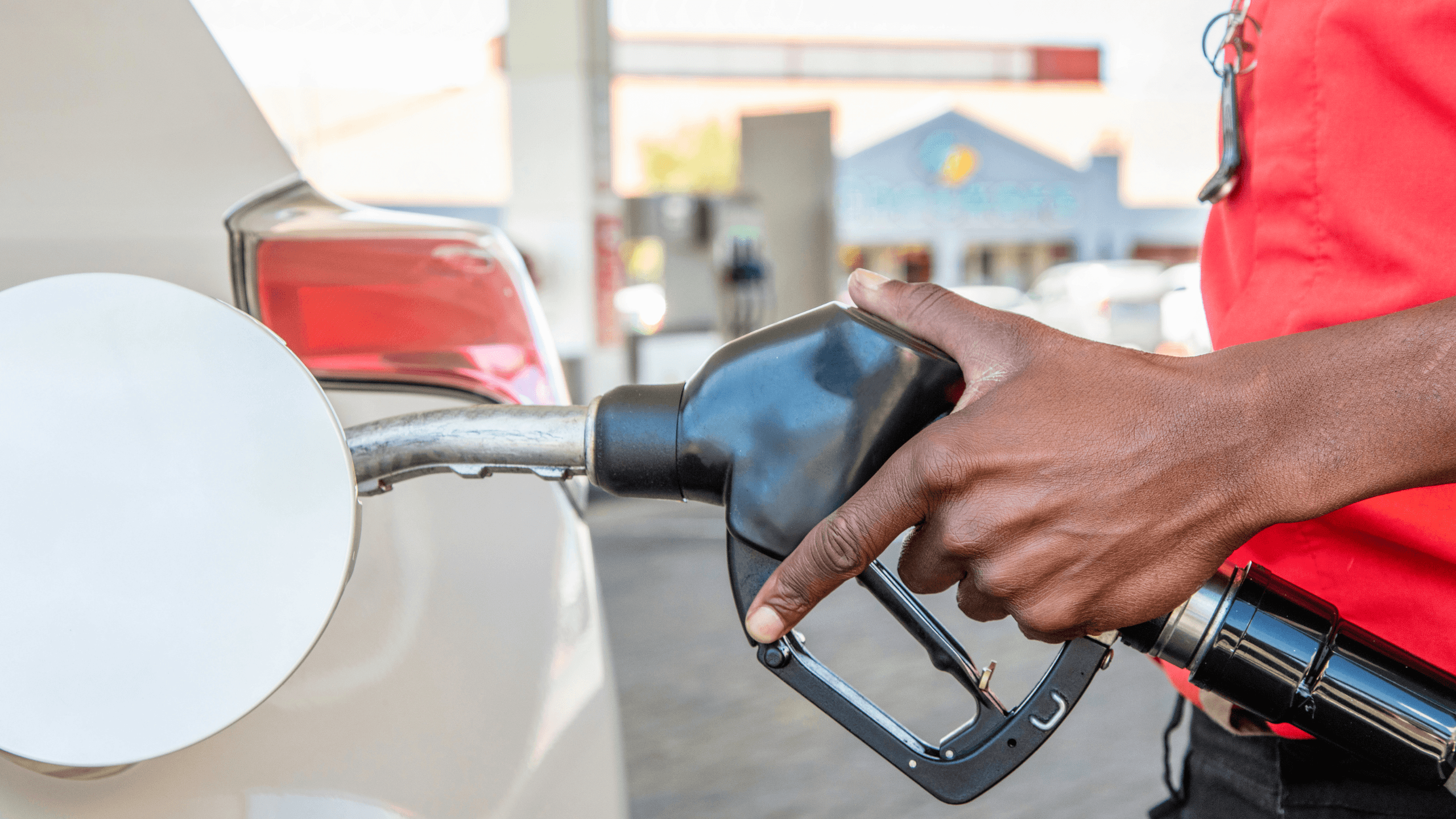African man Hand on Nozzle Pouring petrol in a vehicle